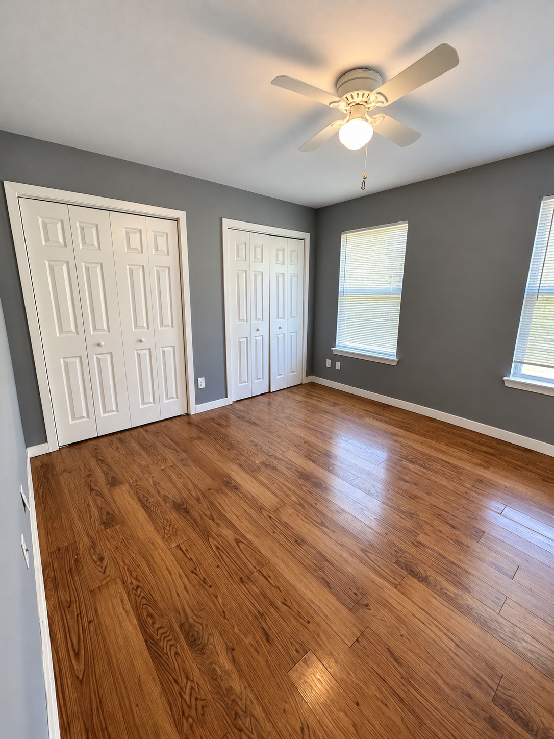 Bedroom with gray walls, white trim and wood-tone floor